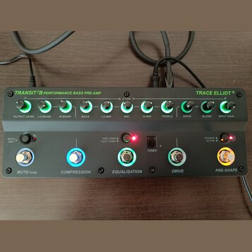 Šedý basový předzesilovač s nápisy TRANSIT B PERFORMANCE BASS PRE-AMP a TRACE ELLIOT. Horní řada obsahuje deset otočných ovladačů s podsvícením a pop…