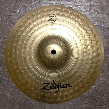 Zlatý kovový činel typu splash s hlouboko kladeným povrchem. Na spodní části je viditelné logo Zildjian a v horní části nápis SPLASH s logem Z. Na pr…