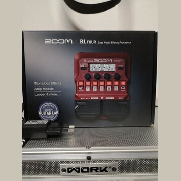Červený basový efektový procesor Zoom B1 FOUR v originální krabici. Na zařízení jsou viditelné nápisy „B1 FOUR“, „ZOOM“ a „Multi-Effects Processor“.…