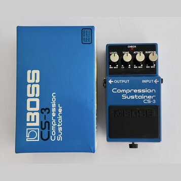 Modrý kytarový pedál s nápisem Compression Sustainer CS-3 a logem BOSS. Efekt má čtyři ovládací knoflíky označené LEVEL, TONE, ATTACK a SUSTAIN, červ…