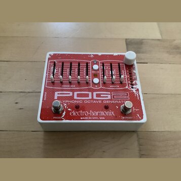 Kytarový efekt pedál v bílém šasi s červeným horním panelem. Na panelu je nápis POG2 POLYPHONIC OCTAVE GENERATOR a značka electro-harmonix MADE IN NY…
