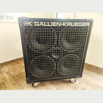 Černý basový reproduktor s kovovou mřížkou, za kterou jsou vidět čtyři velké membrány. V horní části je bílý nápis GALLIEN-KRUEGER a logo GK. Box sto…