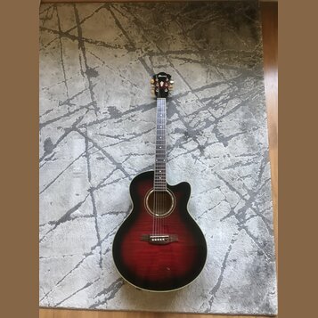 Akustická kytara s vyřezem (cutaway) v červenohnutém sunburst provedení. Na hlavě je viditelné logo Ibanez. Hриф má bílé polohovací značky a kytara j…