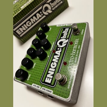 Zelený efekt pedál s nápisem ENIGMA:Qballs for Bass a značkou electro-harmonix MADE IN NYC, USA. Zařízení má osmi černých otočných knoflíků a dva sto…