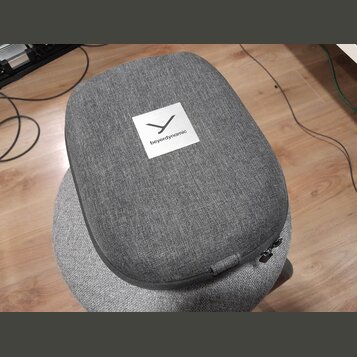 Šedý textilní pouzdro s zipem. Na horní straně je bílý čtverečkový štítek s logem a nápisem beyerdynamic. Povrch textily je v dobrém stavu bez vidite…