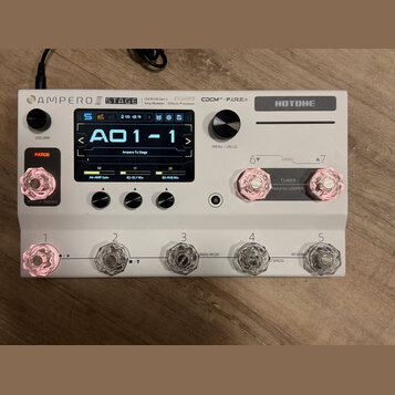 Bílý efektový procesor Hotone Ampero II Stage. Na horní straně jsou nápisy AMPERO II STAGE, Hotone a popis CCDM HD Gen 2 Amp Modeler / Effects Proces…