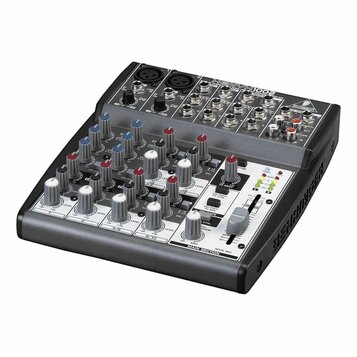 Míchací pult značky BEHRINGER, model XENYX 1002. Zařízení má šedý povrch s černými detaily, obsahuje řadu potenciometrů, posuvníků a vstupních konekt…