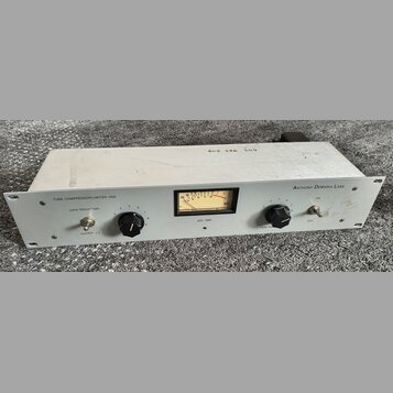 Bílý rackový kompresor s nápisy TUBE COMPRESSOR/LIMITER 1000 a ANTHONY DEMARIA LABS. Na předním panelu se nachází VU metr s označením ADL 1000, dva č…