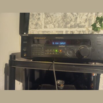Černý AV receiver značky SONY s digitálním displejem, na kterém svítí nápis 5.1CH INPUT. Na předním panelu jsou viditelné nápisy Digital Audio/Video…