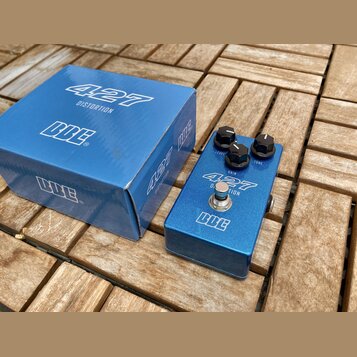 Modrý kytarový efekt v kovovém šasi s nápisy 427 DISTORTION a logo BCE. Na horní straně jsou tři černé otočné knoflíky s popisky LEVEL, GAIN a TONE.…