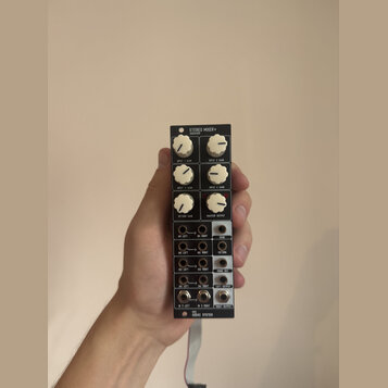 Černý kompaktní stereo mixér s bílými ovládacími knoflíky. Na horní části je nápis STEREO MIXER+ a pod ním AUDAC810. Zařízení obsahuje čtyři knoflíky…