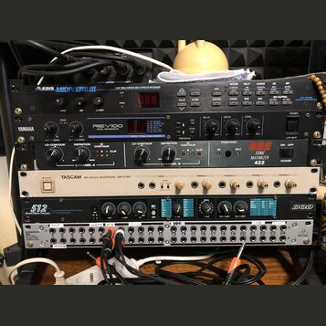 Sestupka rackových zařízení v černém a stříbrném provedení. Z horní části dolů jsou viditelné nápisy: ALESIS MIDIVERB III, YAMAHA REV100 DIGITAL REVE…