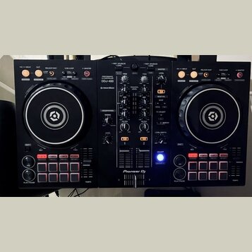 Černý DJ controller s dvěma jogovými koly a centrálním míchacím panelem. Na horní části je nápis PERFORMANCE CONTROLLER DDJ-400 a logo rekordbox, v d…