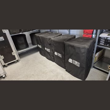 Pět černých transportních krytů z látky, které jsou umístěny v řadě na podlaze a polici. Na každém krytu je bílý nápis dB TECHNOLOGIES. Povrch látky…