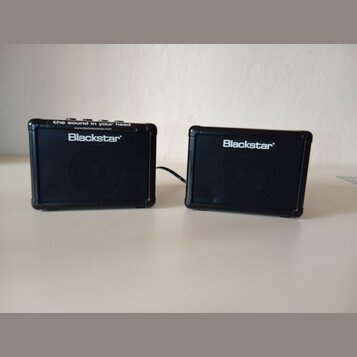 Dvě černé kompaktní reproduce s logem Blackstar. Levý kus má na horní hraně nápis the sound in your head a webovou adresu www.blackstaramps.com. Oba…