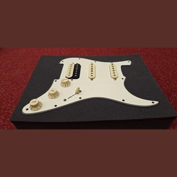 Bílá pickguard pro elektrickou kytaru s třemi snímači. První snímač zleva je kombinovaný, má bílou a černou část; zbývající dva jsou bílé. Na desce j…