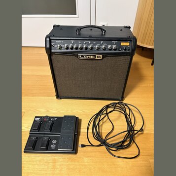 Černý kytarový kombo zesilovač s nápisem SPIDER IV 75 a logem LINE 6. Přední panel obsahuje ovládací knofíky, přepínače a zelenou kontrolku. Před zes…