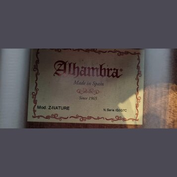 Fotografie detailu štítku uvnitř hudebního nástroje. Na štítku je červeným písmem nápis Alhambra, pod ním text Made in Spain a Since 1965. V dolní čá…