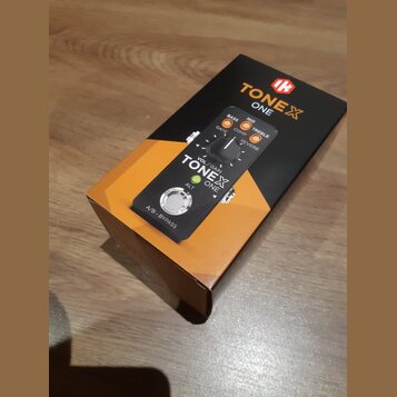 Krabice s kytarovým pedálem TONEX ONE. Na obalu je zobrazen černý kompaktní pedal s ovládacím knoflíkem, zelenou LED diodou a nápisy VOL/GAIN, ALT a…