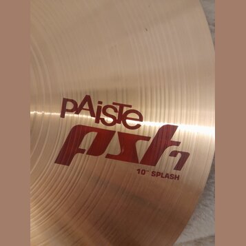 Detail kovového činely v zlatavé barvě s viditelným koncentrickým broušením. Na povrchu je červený nápis pAiste, pod kterým je stylizovaný červený ná…