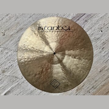 Kruhová mosazná činely s kladivkovaným povrchem. Na horní části je černý nápis istanbul® a Agop Handmade cymbals from Turkey. Ve spodní části je čtve…