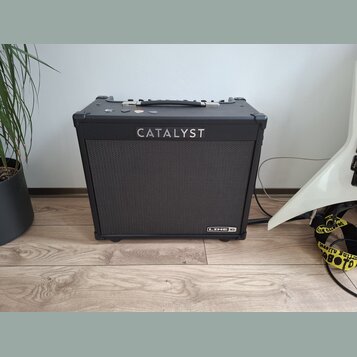 Černý kytarový kombo zesilovač s látkovou mřížkou. Na přední straně je nápis CATALYST a v pravém dolním rohu logo LINE 6. Horní strana obsahuje úchyt…