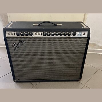 Kytarový kombo zesilovač v černém krytu s šedou textilní mřížkou. Na předním panelu je nápis Fender a vpravo označení TWIN REVERB. Ovládací panel obs…