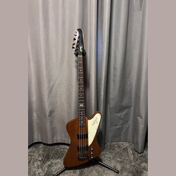 Hnědá elektrická basová kytara s bílým plechtrátorem. Na hlavě je viditelné logo Rickenbacker a na plechtrátoru je nápis Rickenbacker s doprovodným l…