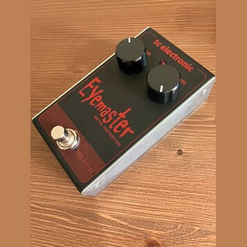 Kytarový efekt v kovovém šasi s černým horním panelem. Na panelu je červený nápis Eyemaster a pod ním text METAL DISTORTION, v pravém horním rohu je…