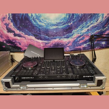 Černý DJ 컨트롤러 Denon DJ umístěný v hliníkovém transportním kufru. Na přístroji je vidět nápis DENON DJ a logo engine dj. Zařízení má dvě otáčivé jog-k…