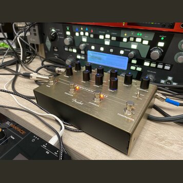 Kovový kytarový efekt v bronzové barvě s nápisem DOWNTOWN REVERB a logem Fender. Zařízení má několik ovládacích knoflíků, přepínače Equalizer a Overd…
