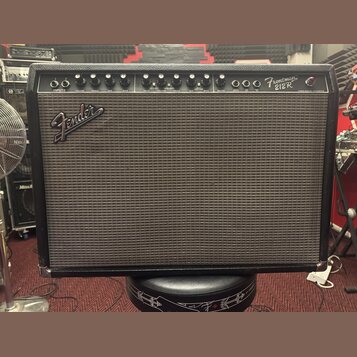 Černý kytarový kombo zesilovač s látkovou mřížkou. Na předním panelu je nápis Frontman 212R a logo Fender. V horní části jsou umístěny ovládací knofl…