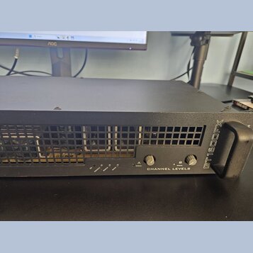 Černý rackový zesilovač s kovovým šasi a madlem na pravé straně. Na předním panelu je nápis GT1600FX a CHANNEL LEVELS, několik kontrolních LED diod s…
