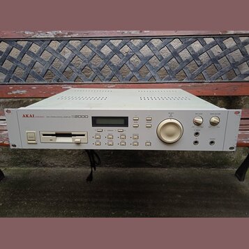 Bílý rackový MIDI sampler s nápisem AKAI professional MIDI STEREO DIGITAL SAMPLER S2000. Přední panel obsahuje floppy disketovou mechaniku, LCD displ…