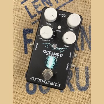 Černý efektový pedál s bílými ovládacími knoflíky. Na spodní části je nápis electro-harmonix a uprostřed název modelu OCEANS 11 REVERB s grafickým mo…