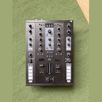 Černý DJ kontroler s nápisem TRAKTOR KONTROL Z2 a logem NI v pravém horním rohu. Zařízení obsahuje dva kanály s knoflíky Gain, Mid a Low, faderem hla…
