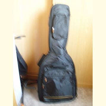 Černý polstrovatý pouzdro (gig bag) na hudební nástroj. Má dvě zipové kapsy, jednu úzkou v horní části a jednu širší ve spodní části. Povrch materiál…