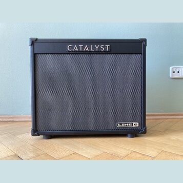 Černý kytarový kombo zesilovač s látkovou maskou reproduktoru. V horní části je bílý nápis CATALYST a v pravém dolním rohu se nachází logo LINE 6. Ná…