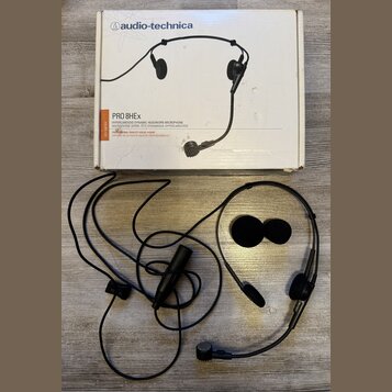 Fotografie zobrazuje černé náhlavní mikrofony a jeho původní krabici. Na krabici je nápis audio-technica a model PRO 8HEx s popisem HYPERCARDIOID DYN…