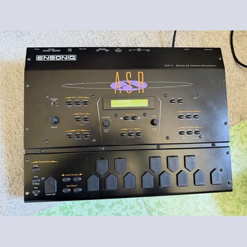 Černý sampler Ensoniq ASR-X Advanced Sampler/Resampler. Zařízení má LCD displej, několik tlačítek a ovládacích prvků s nápisy jako Disk / Global, Eff…