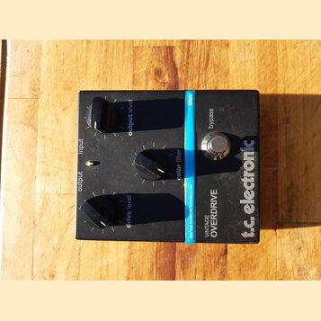 Černý kytarový efekt s nápisy t.c. electronic a VINTAGE OVERDRIVE. Na horní straně jsou tři černé otočné knoflíky s popisky output level, color filte…