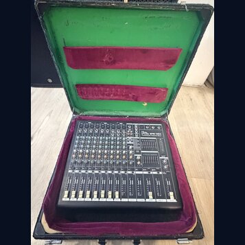 Černý mixážní pult v přepravním kufru s fialovou a zelenou výstelkou. Na přístroji je nápis "Behringer DFM 1094 Professional Powered Mixer". Jsou vid…