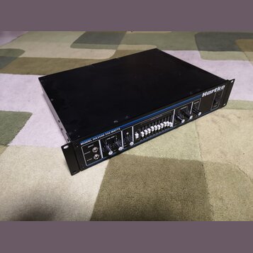 Černý rackový zesilovač s modrými detaily. Na předním panelu je nápis MODEL HA3500 350 WATTS a logo Hartke. Zařízení obsahuje několik regulačních kno…