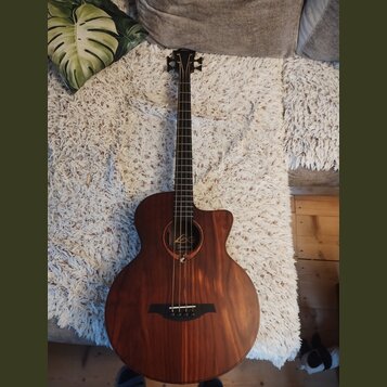 Akustická kytara s hnědým dřevěným povrchem a výřezem v těle. U otvoru je viditelné logo „Leko“ a pod ním nápis „Guitar“. Nástroj je v dobrém stavdu…