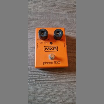 Oranžový kytarový efekt s dvěma černými oválovými knoflíky. Na přední straně je logo MXR v obdélníku a nápis phase 100. Jsou zde také označení OUTPUT…