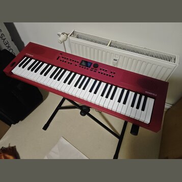 Červený digitální klavír značky Roland, model GO:KEYS 3. Nástroj je umístěn na černém skládacím stojanu. Povrch je v dobrém stavu bez viditelného opo…