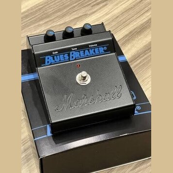 Černý kytarový efekt pedál značky Marshall s nápisem Blues Breaker. Na horní straně jsou tři ovládací knoflíky s popisky Gain, Tone a Volume. V dolní…