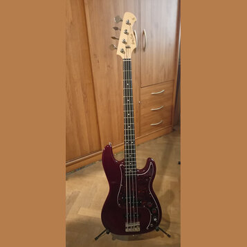Tmavě červená elektrická basová kytara s tmavým hmatníkem a červeně vzorovaným pickguardem. Na hlavě nástroje je viditelné logo "Music Man". Kytara s…