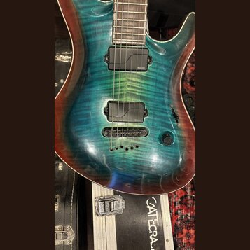 Elektrická kytara s modrozelým plamenovým javorovým topem a hnědými okraji. Nástroj má dva černé humbuckery, na kterých je viditelný nápis FISHMAN. K…