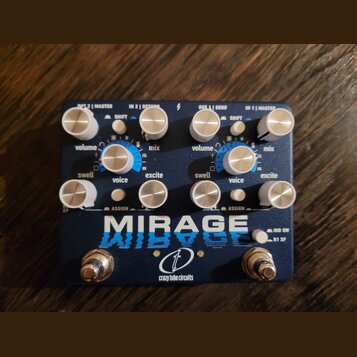 Modrý kytarový efekt s nápisem MIRAGE a logem crazy tube circuits. Zařízení má osm stříbrných otočných knoflíků s popisky swell, volume, voice, mix a…